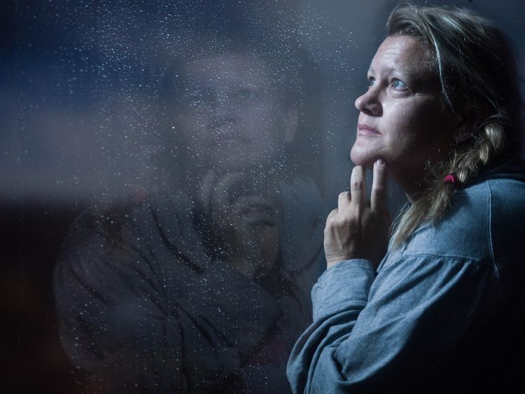 woman next to a window thinking about her mental health
