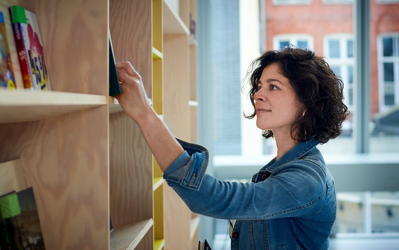 woman searching for the right book on a bookshelf